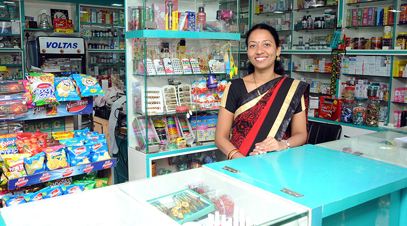 Woman selling at counter in a shop in rural India.