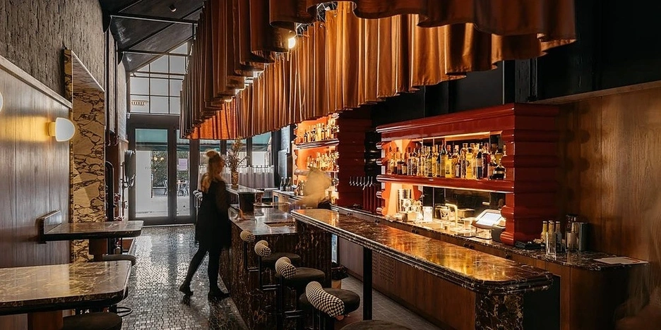 Woman stands at a bar in an empty restaurant