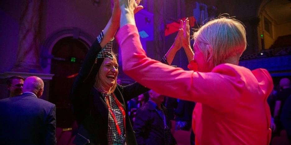 Two woman giving each other a high ten smiling