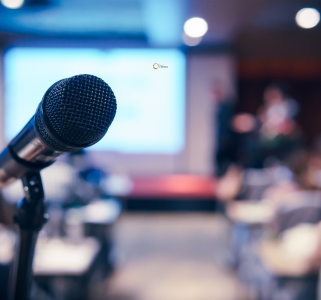 A close-up of a microphone on a stand, positioned on an empty stage, ready for a speaker to begin