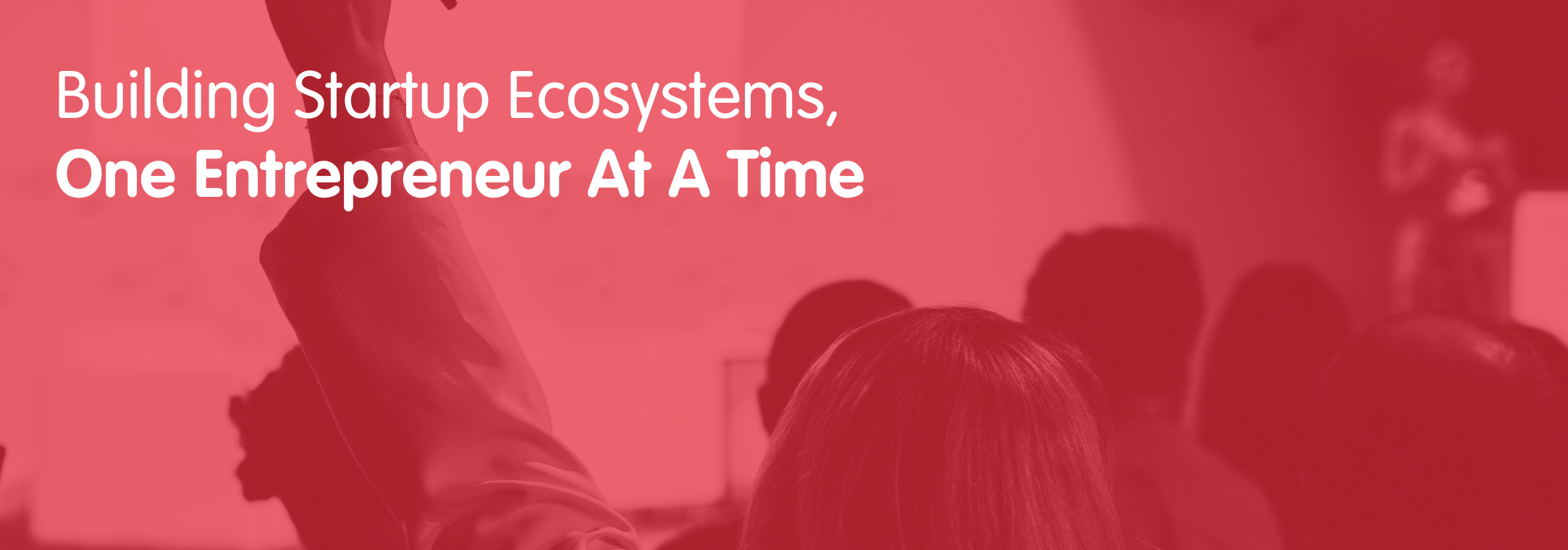 group of people listening to presenter, one with their hand up