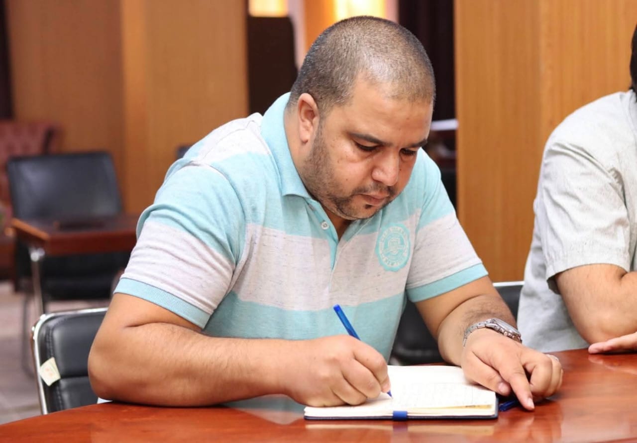 Image of the university interface representatives, institute directors, and deputy directors of the University Center of Illizi attending the coordination meeting to prepare the Global Entrepreneurship Week program, gathered around the table discussing upcoming activities.