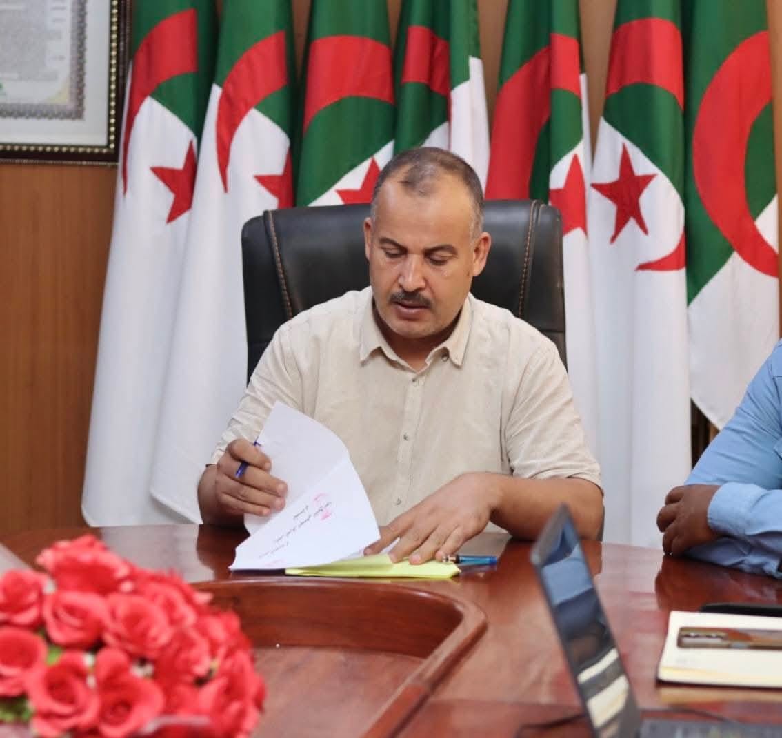 Image of the university interface representatives, institute directors, and deputy directors of the University Center of Illizi attending the coordination meeting to prepare the Global Entrepreneurship Week program, gathered around the table discussing upcoming activities.