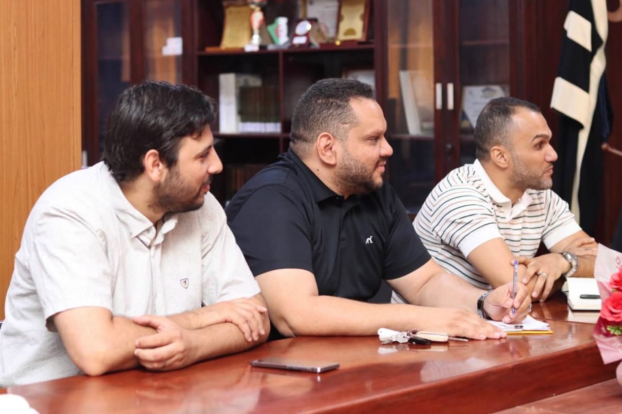 Image of the university interface representatives, institute directors, and deputy directors of the University Center of Illizi attending the coordination meeting to prepare the Global Entrepreneurship Week program, gathered around the table discussing upcoming activities.