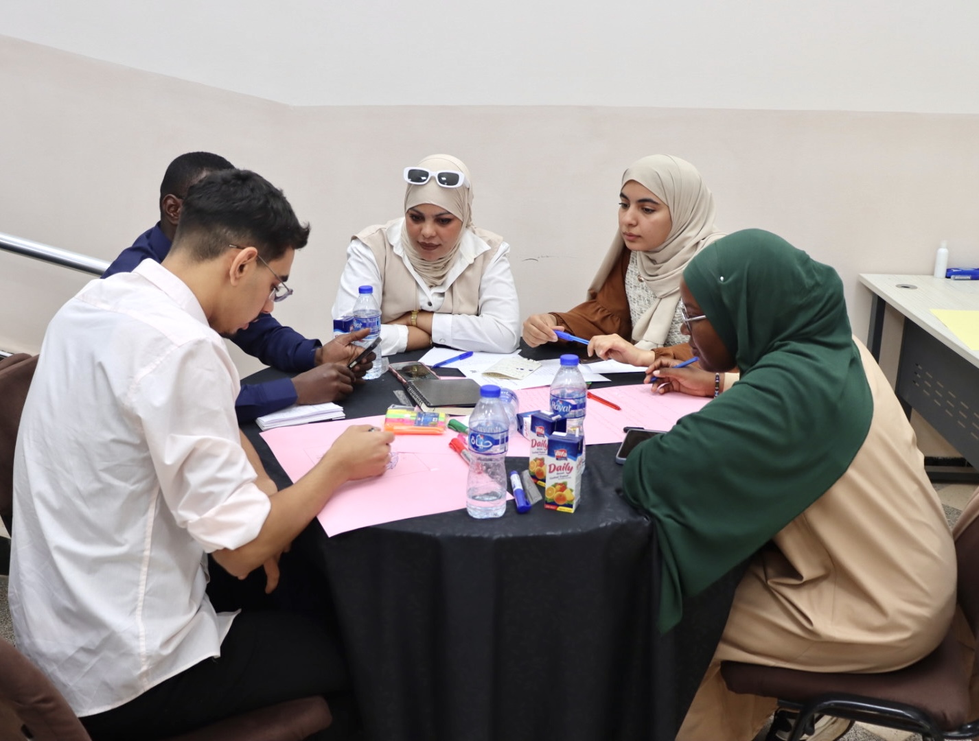 Image of the student teams participating in the Illizi Hackathon 2025, showing team members collaborating in the coworking space to develop innovative solutions for the announced challenge during Global Entrepreneurship Week.