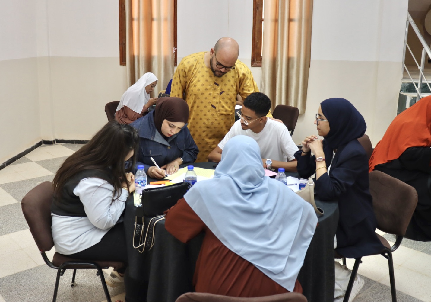 Image of Dr. Khathir Chine, Director of the Business Incubator at the University Center of Illizi, observing the participating teams during the Illizi Hackathon 2025, monitoring their progress and providing guidance as they develop their solutions in the coworking space.