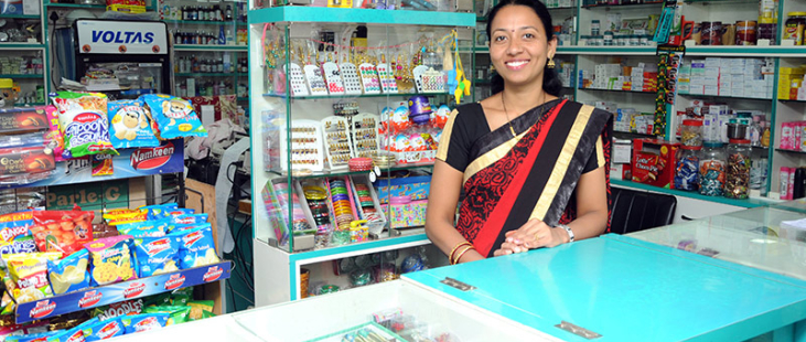 Woman selling at counter in a shop in rural India.