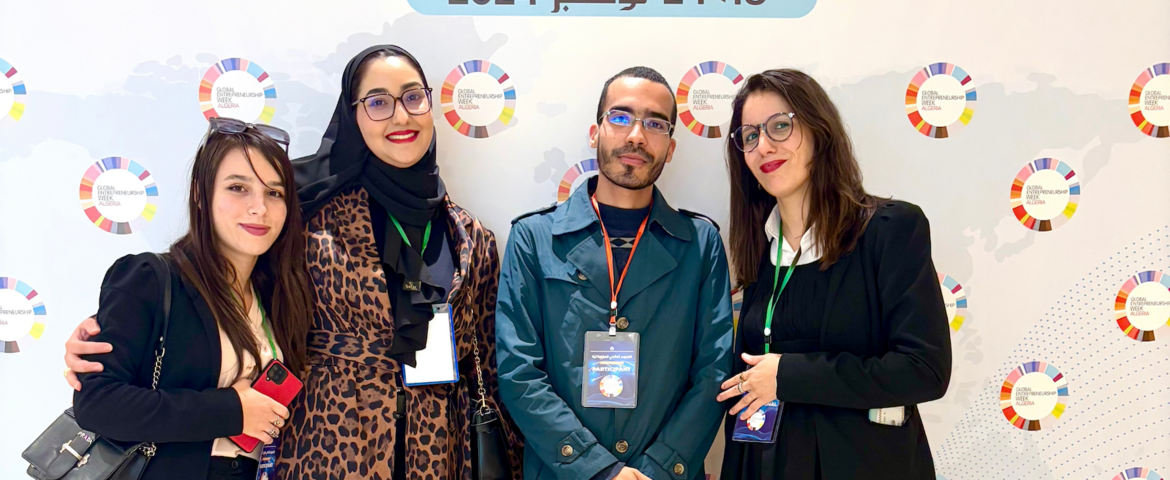 Group of people posing for a photo infront of a wall with the Global Entrepreneurship Week Algeria logo